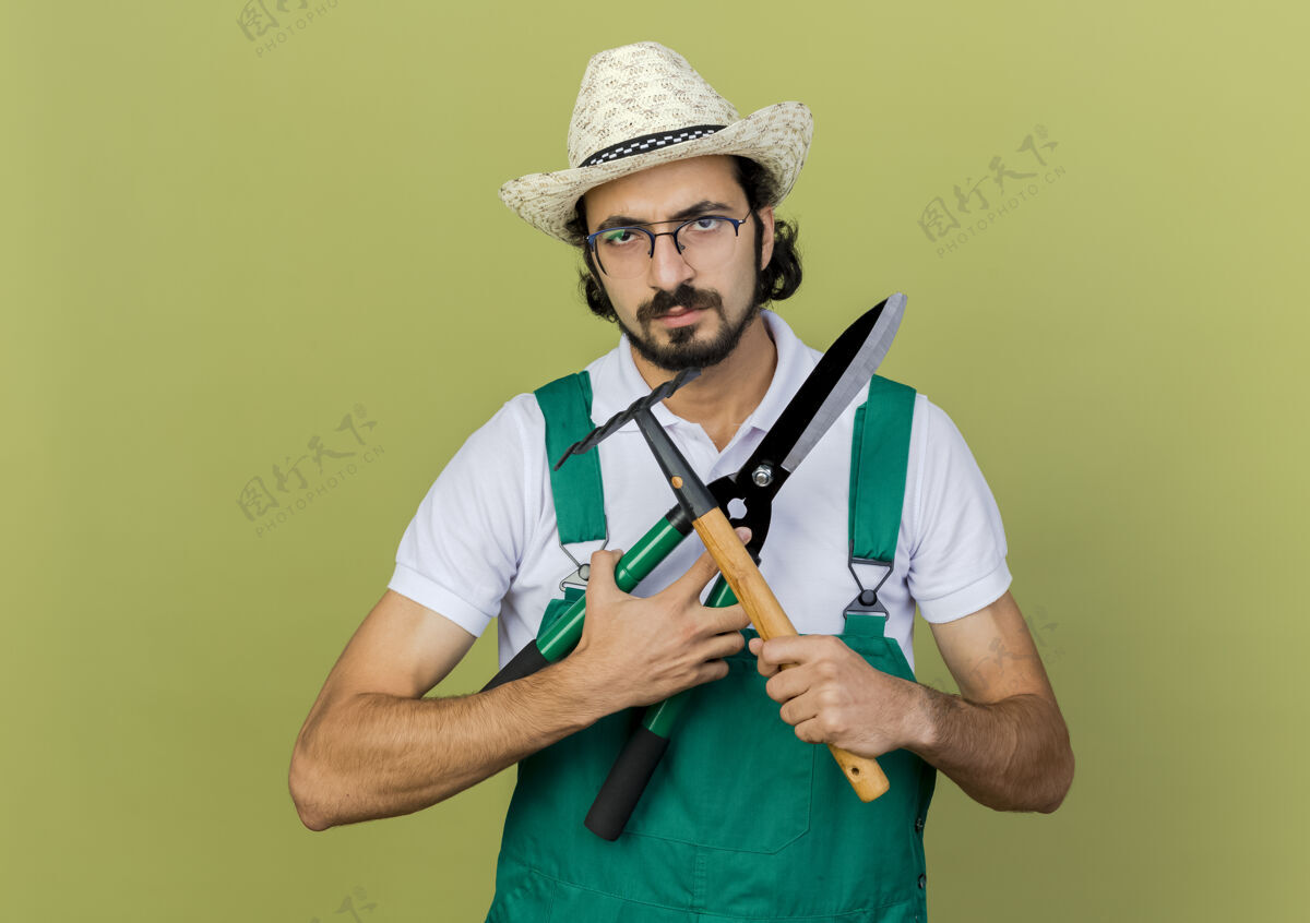 烦恼恼怒的园丁戴着园艺帽戴着眼镜拿着剪刀和耙子橄榄人磨损