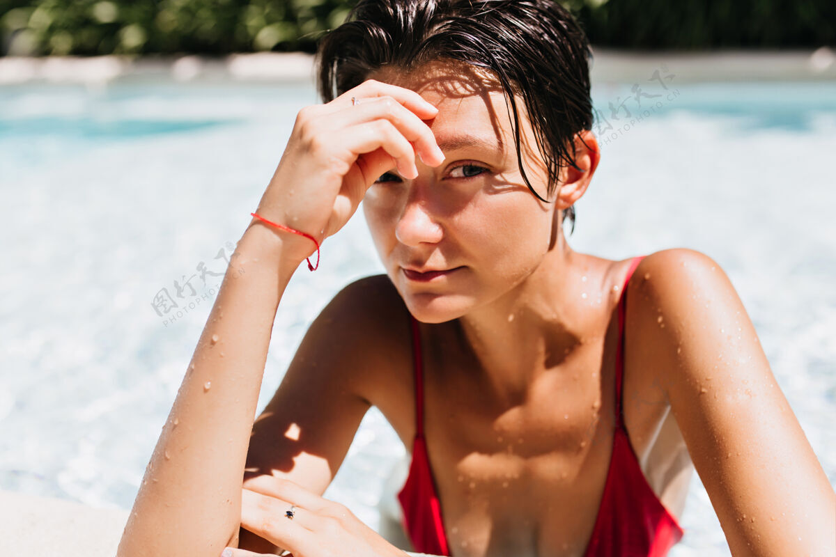 微笑棕发女人的肖像 棕褐色的皮肤在游泳池里放松模特太阳华丽