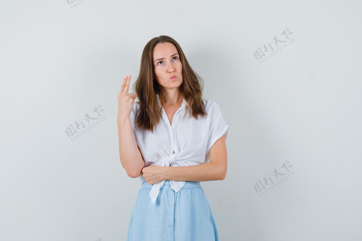 水疗年轻的女士用手和两个手指在衬衫 裙子和看起来沉思人沉思女性