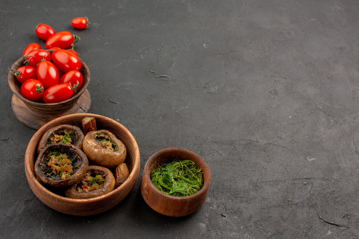 水果前视图煮熟的蘑菇和西红柿在黑暗的桌子上蘑菇野生面食胡椒黑午餐
