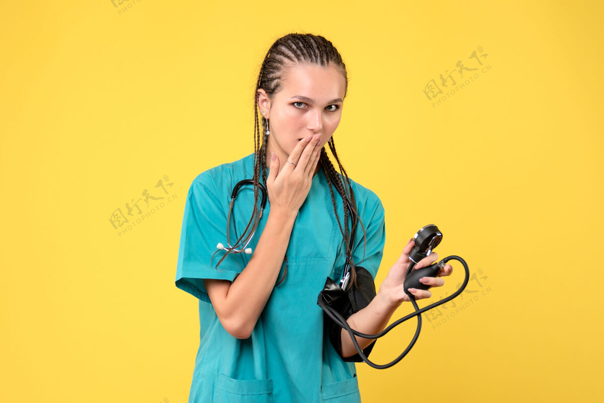 医疗器械身穿医疗服的女医生在黄色墙壁上检查压力的正视图前面仪器健康