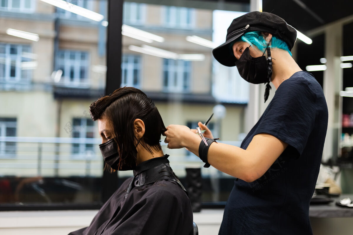 发型师一个专业的女理发师给客户理发这个女孩戴着面具坐在美容院里爆发护理肖像