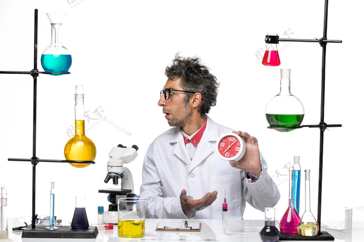 专业前视图身穿医疗服的男科学家手持白色背景上的红色时钟化学冠状病毒实验室健康高尔夫医学医院