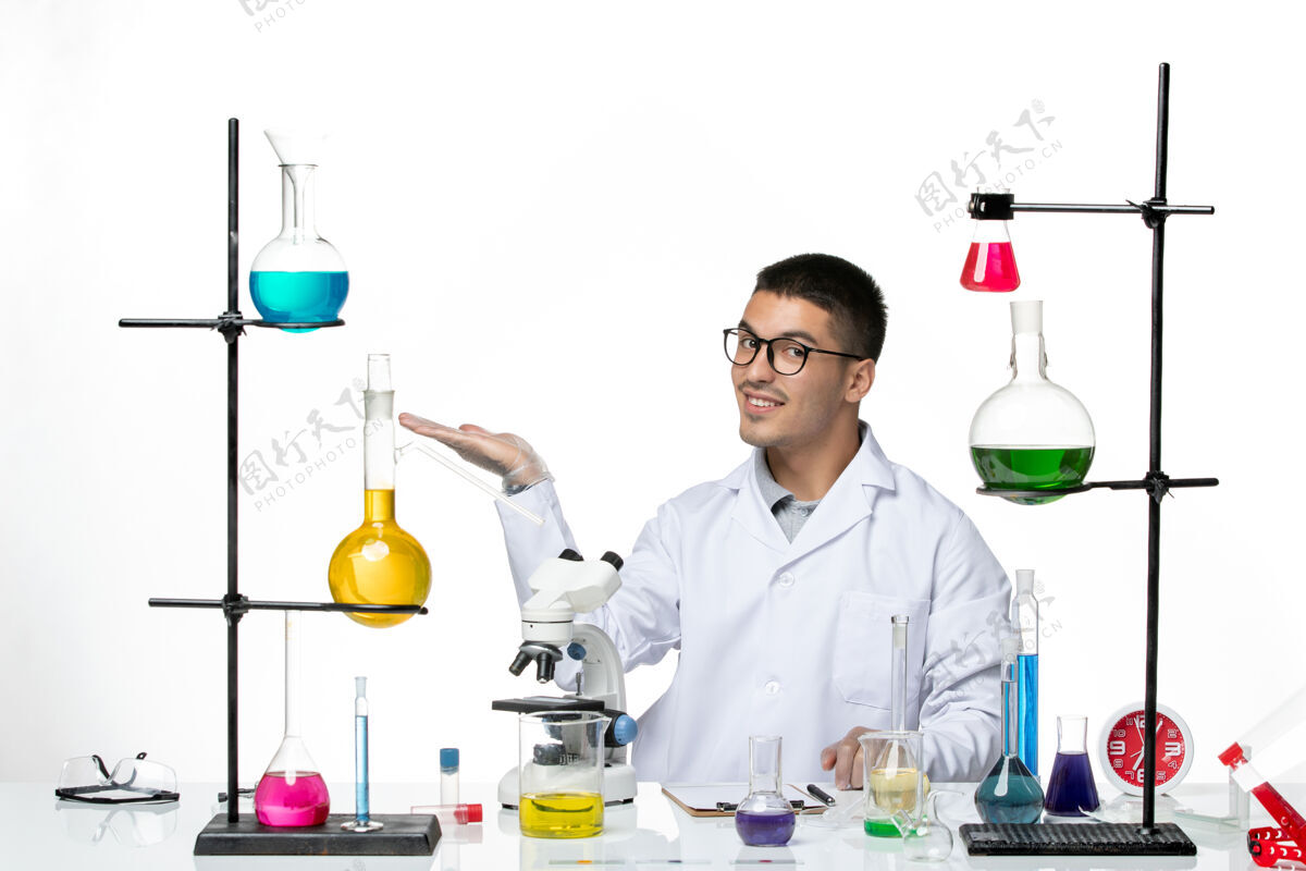 衣服正面图身穿白色医疗服的男性化学家坐在白色背景病毒实验室的柯维德疾病科学上 带着解决方案和微笑实验室前面药