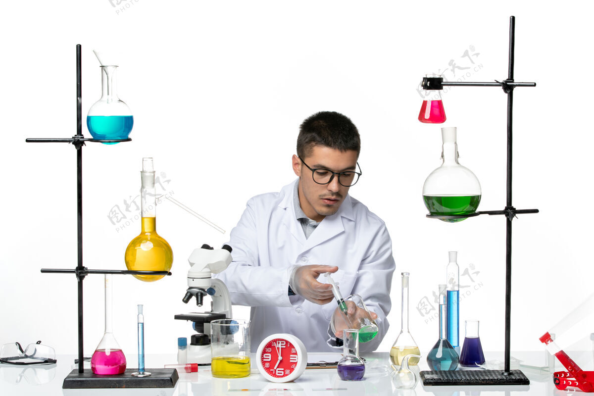 正面前视图身穿白色医疗服的男性化学家在白色背景病毒科学冠状病毒-大流行实验室工作医学溶液罐子