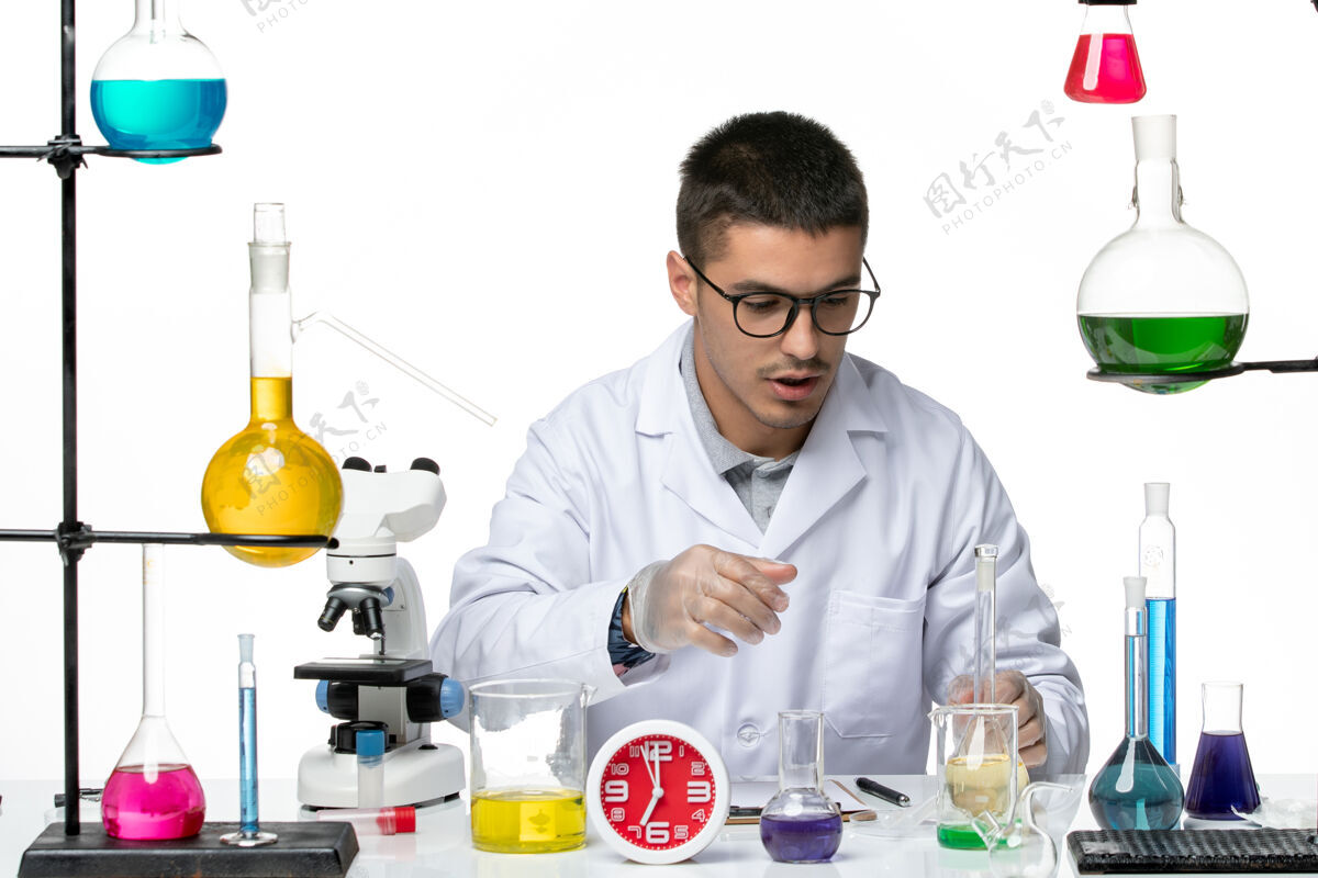 实验室正面图身着白色医疗服的男性化学家在白色背景病毒科学实验室covid大流行上使用不同的解决方案实验室外套大流行专业