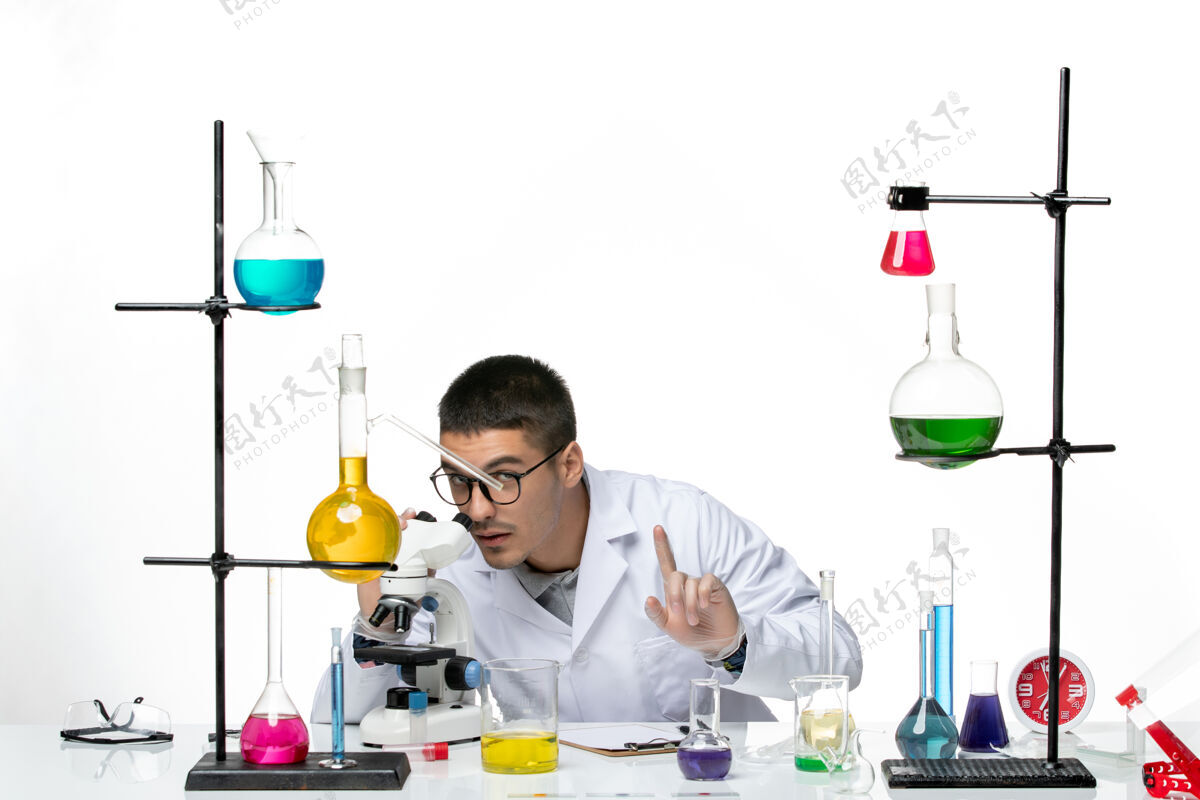 正面前视图男性化学家穿着白色医疗服 在白色背景上用显微镜观察病毒冠状病毒-疾病科学容器化学品罐子