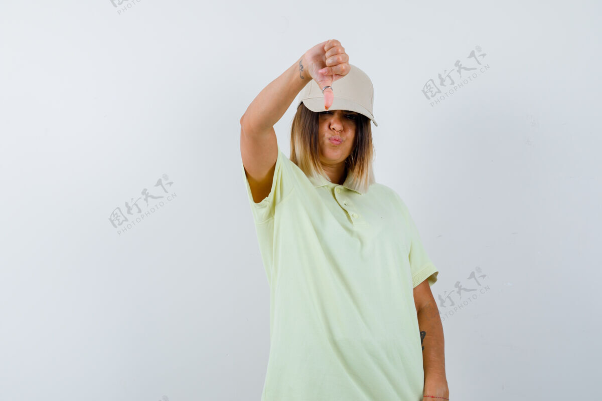 女人一位年轻女士穿着t恤 戴着帽子 大拇指朝下 脸上露出不满的表情头发时尚魅力