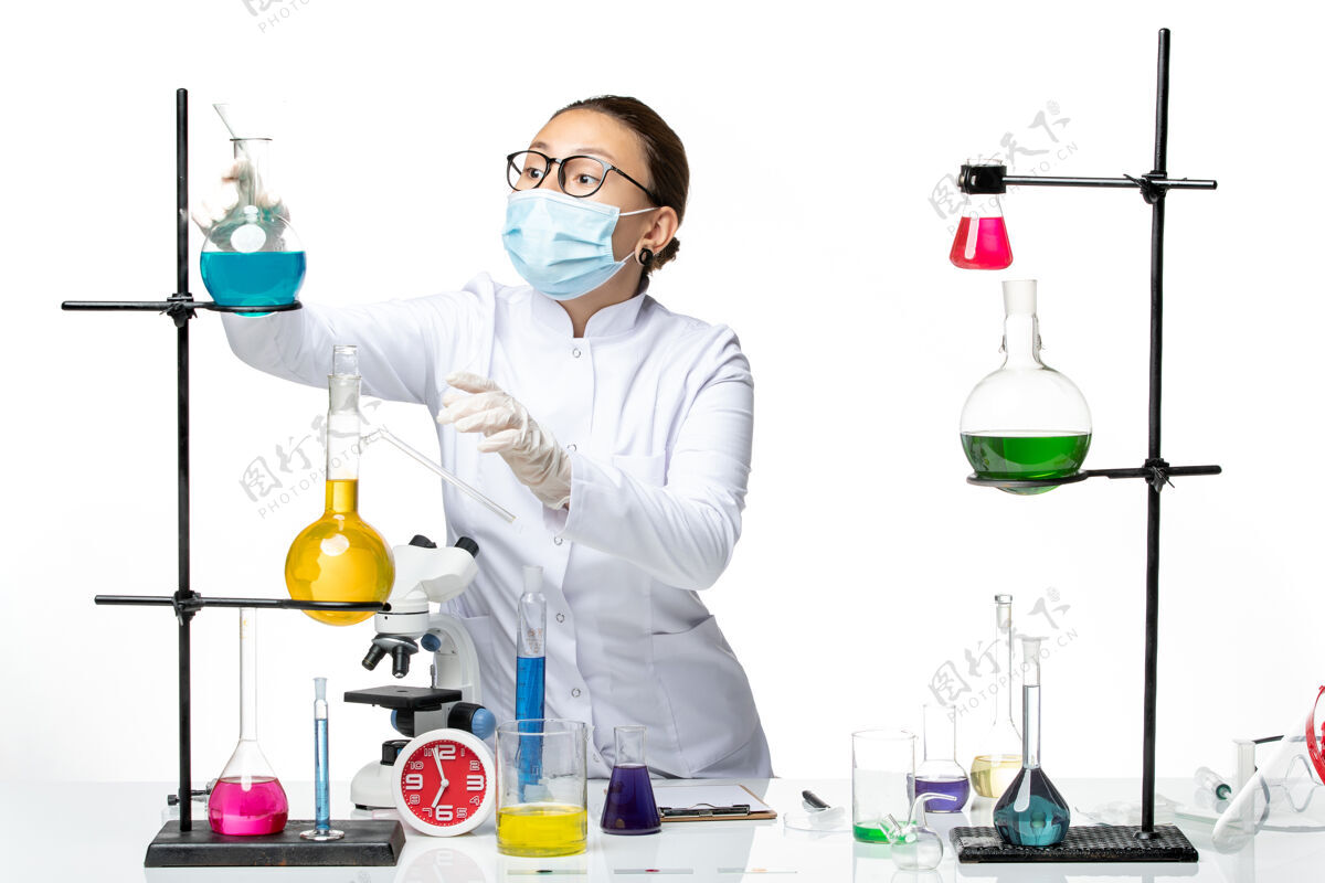 视图前视图：穿着医疗服的女化学家戴着面罩在白色背景上工作病毒化学实验室covidsplash药品病毒套装