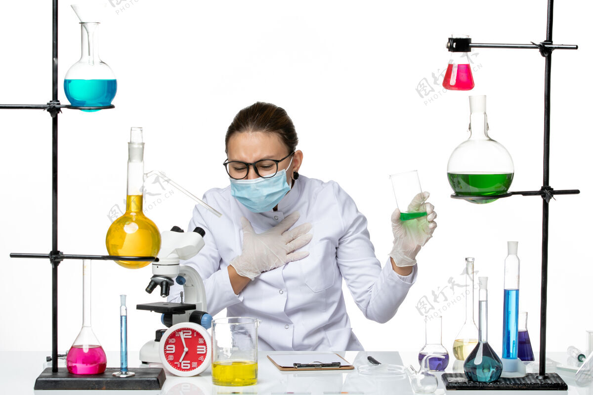医院前视图穿着医疗服的女化学家 白色背景上有面罩保持溶液飞溅实验室病毒化学冠状病毒套装正面喷溅
