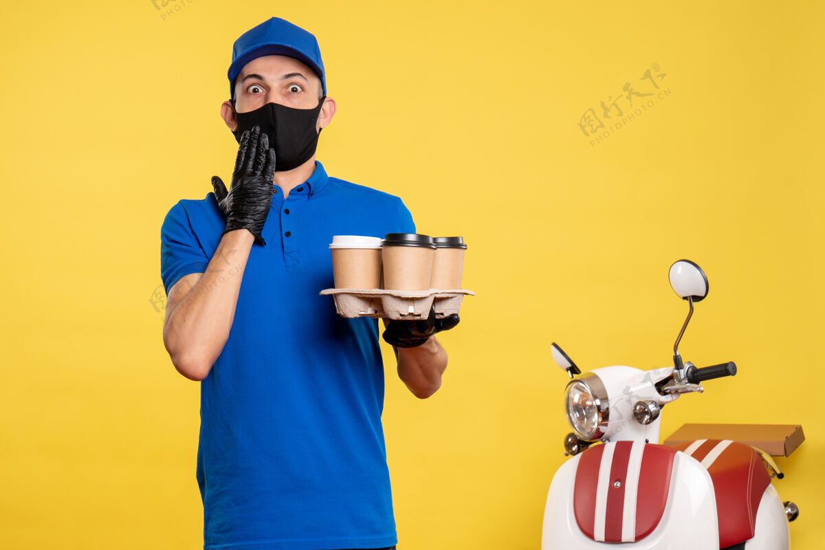 人正面图：戴着黑色面具的男信使拿着咖啡 穿着黄色的工作服递送脸人