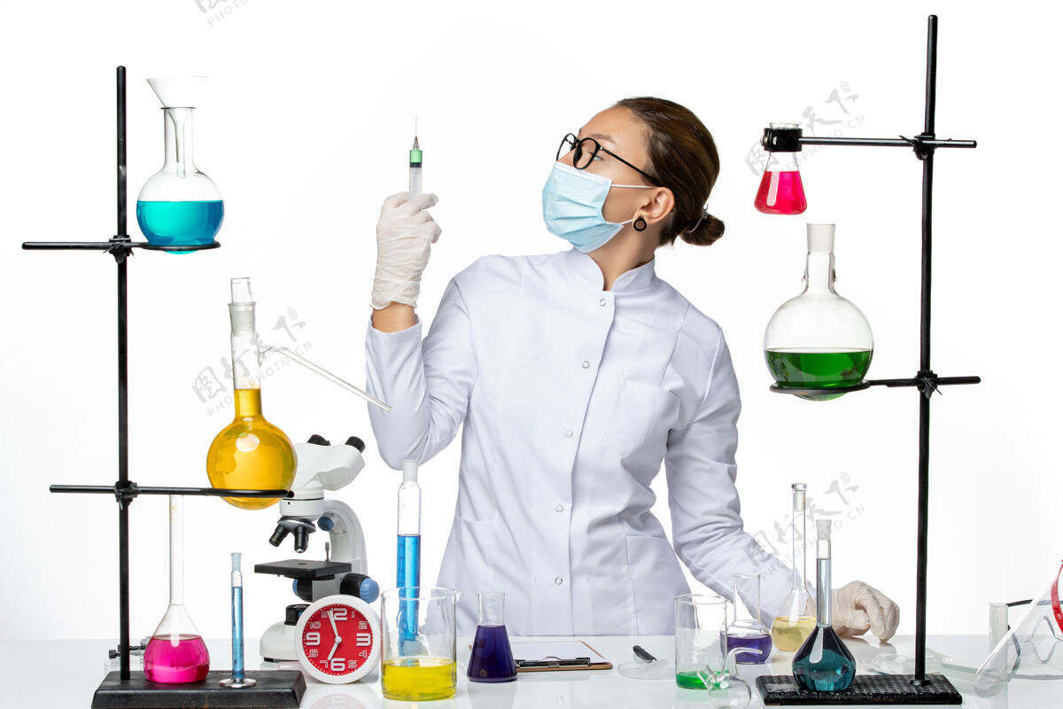 喷溅前视图：身穿医疗服的女化学家 戴着面罩 在白色背景上拿着针剂病毒化学实验室covidsplash医学西装专业