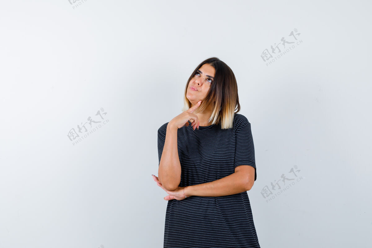 站立穿着黑色t恤的女士站在思考的姿势 看着梦幻般的前景色人现代时尚
