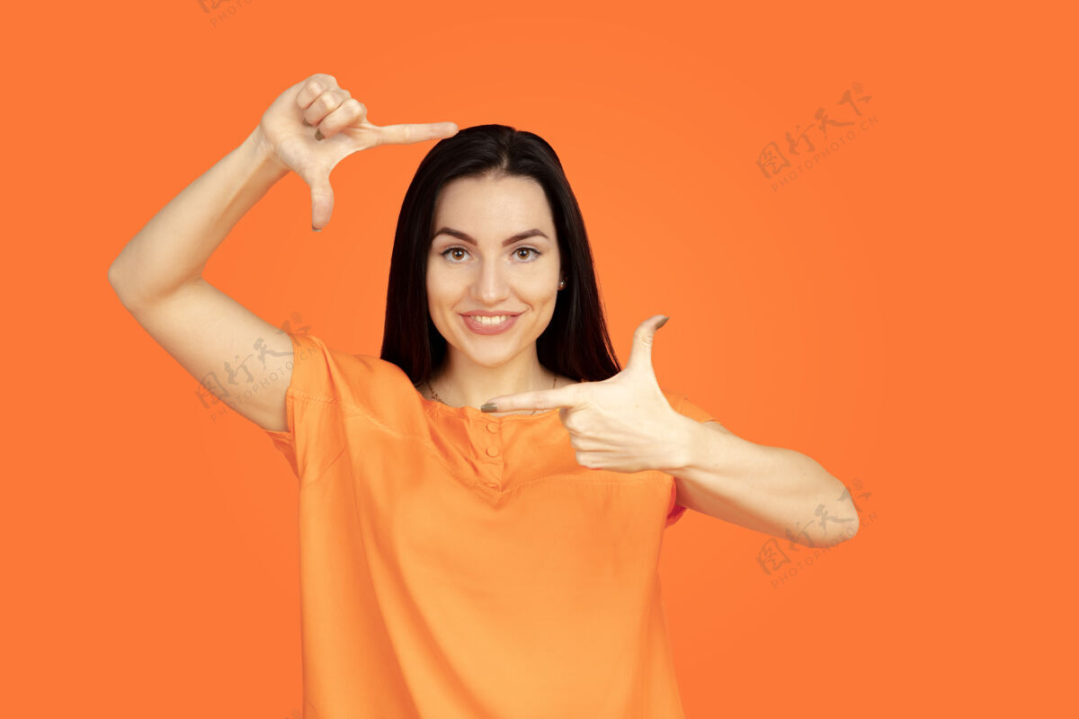职业橙色工作室背景上的白人年轻女子肖像衬衫黑发现代