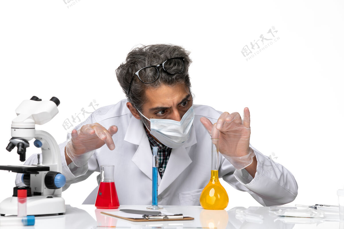 病毒正面近距离观察穿着特殊套装的中年科学家坐在白色背景上拿着解决方案男性病毒科学冠状病毒-化学实验室解决方案坐观点