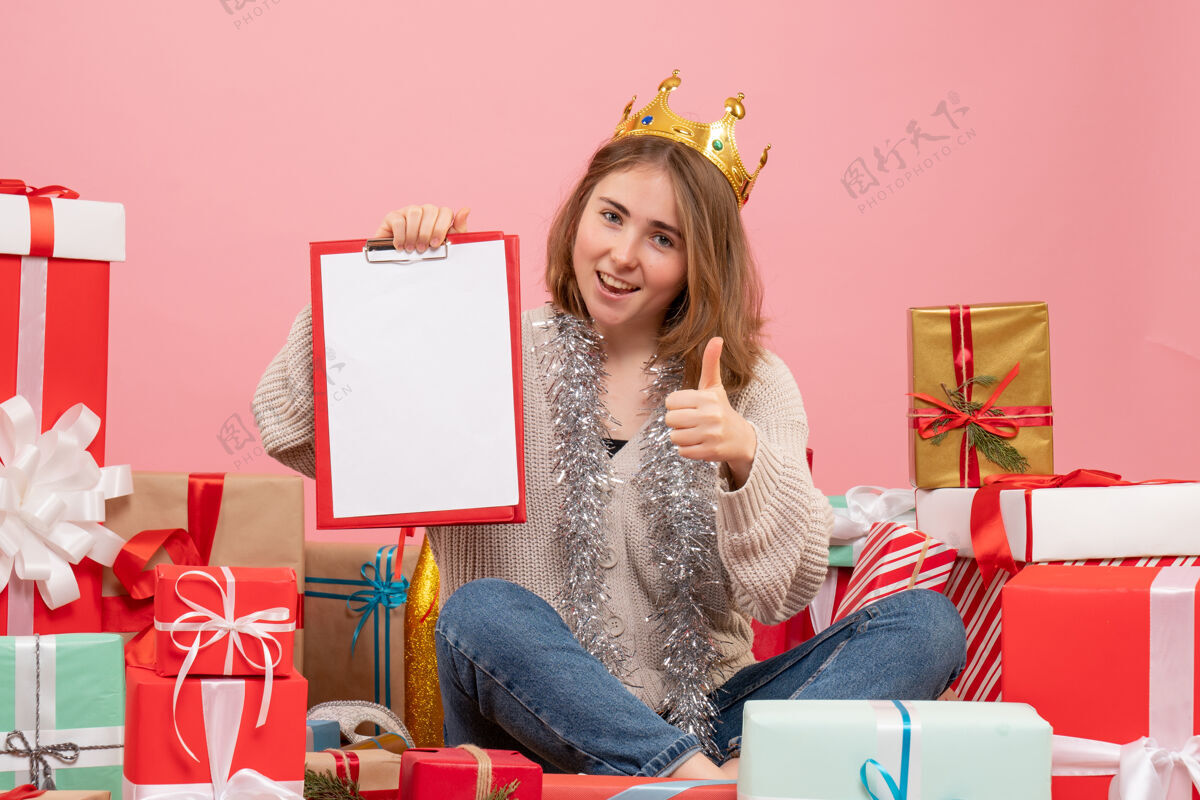 礼物正面图年轻女性围坐在礼物旁边 手里拿着纸条圣诞节手人