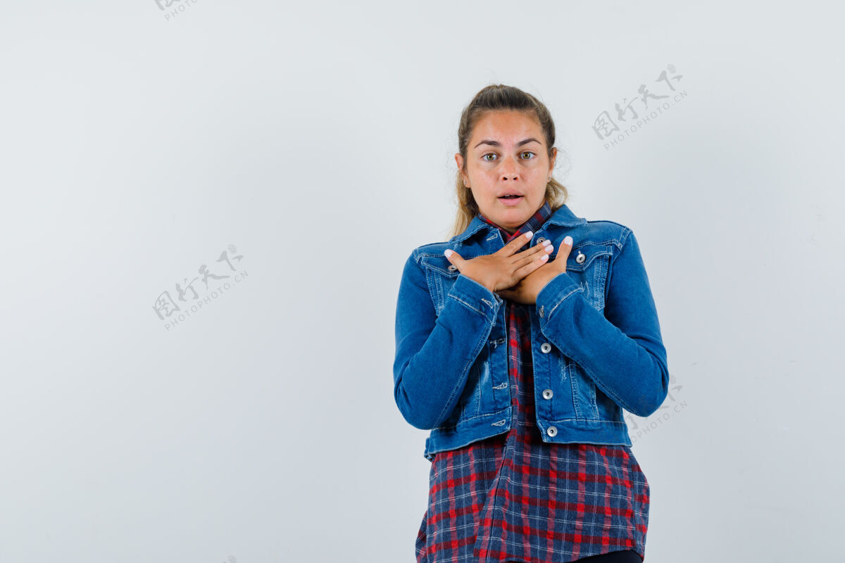 手身穿衬衫 夹克衫的年轻女子双手放在胸前 神情迷惑不解 俯视前方一个胸部正面