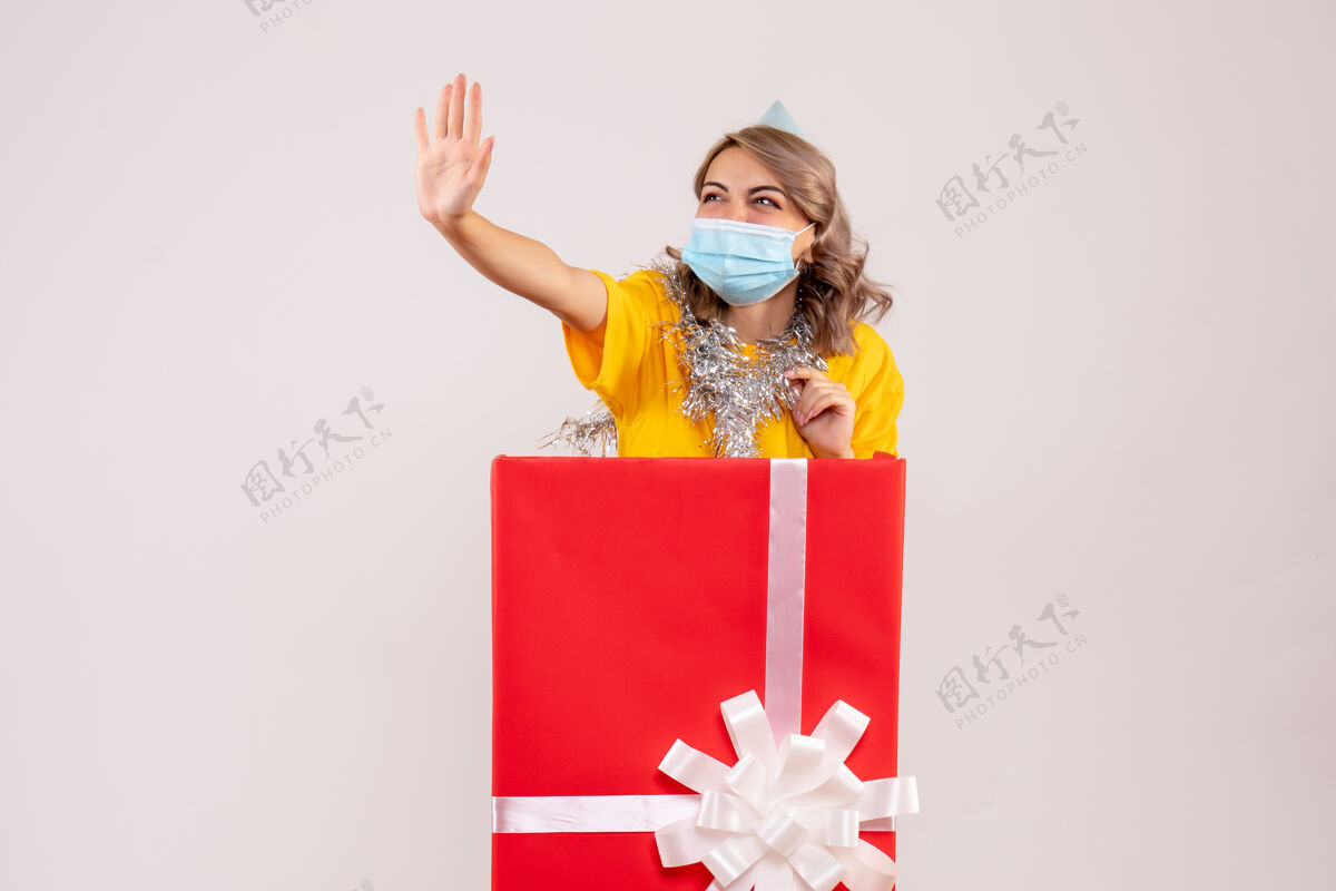 情感正面图：戴着面具的红色礼品盒里的年轻女性快乐丝带病毒