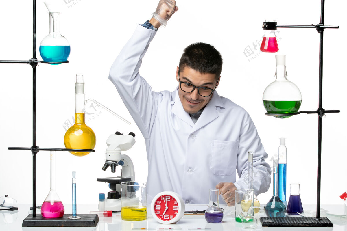 前面前视图穿着白色医疗服的男性化学家坐在白色背景的病毒科学科维大流行实验室里 拿着溶液医生医学病毒