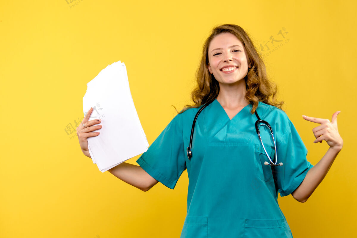 女人黄色墙上的女医生微笑着拿着文件的正面图人前面黄色