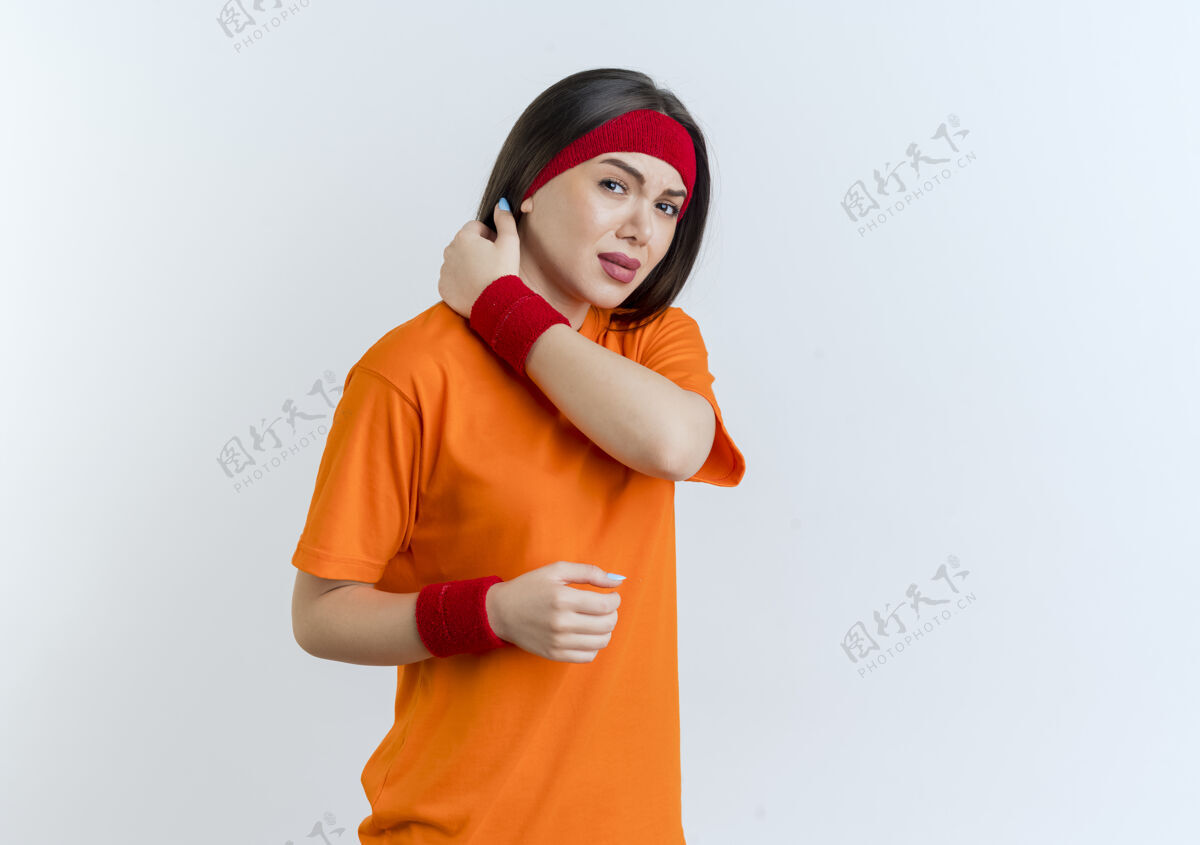 穿戴着头带和腕带的疼痛的年轻运动女性 看起来手在空中触摸着脖子头带疼痛保持