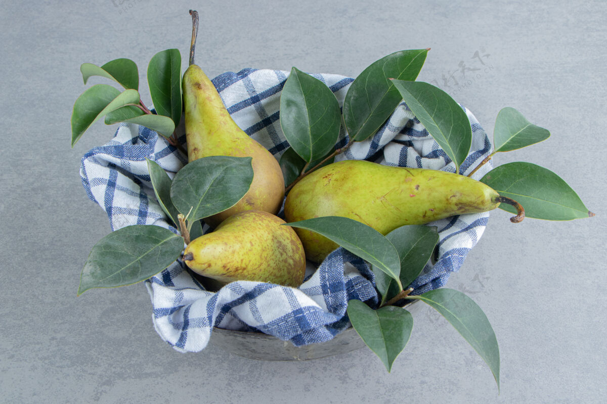 健康梨子和叶子放在一个碗里 用毛巾盖在大理石上配料美味梨
