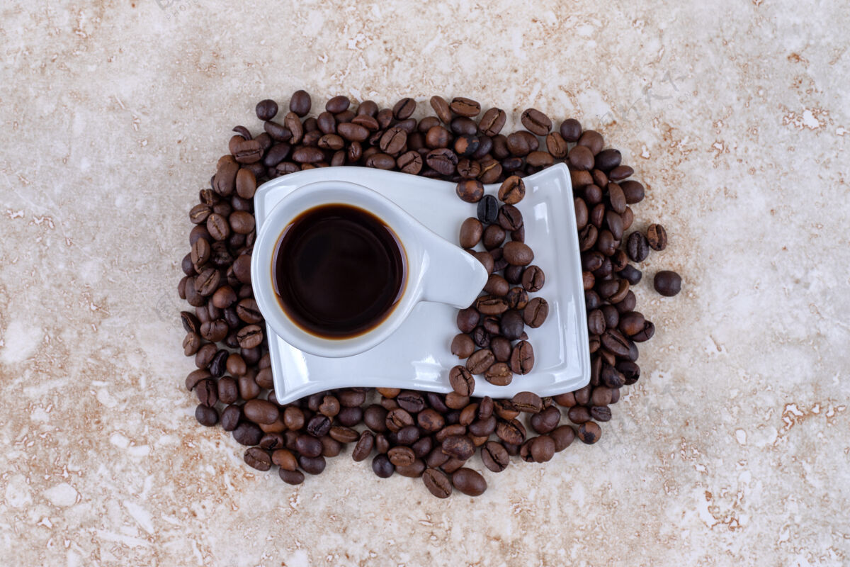 咖啡豆坐在一堆咖啡豆上的茶碟上的一杯咖啡美味芳香香味