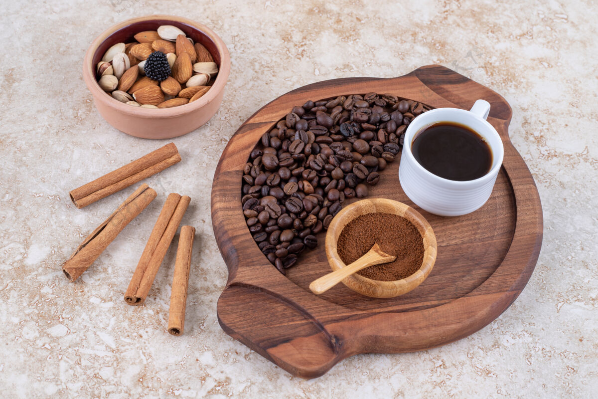 咖啡粉咖啡托盘旁边的肉桂棒和一小碗各式各样的坚果芳香肉桂咖啡