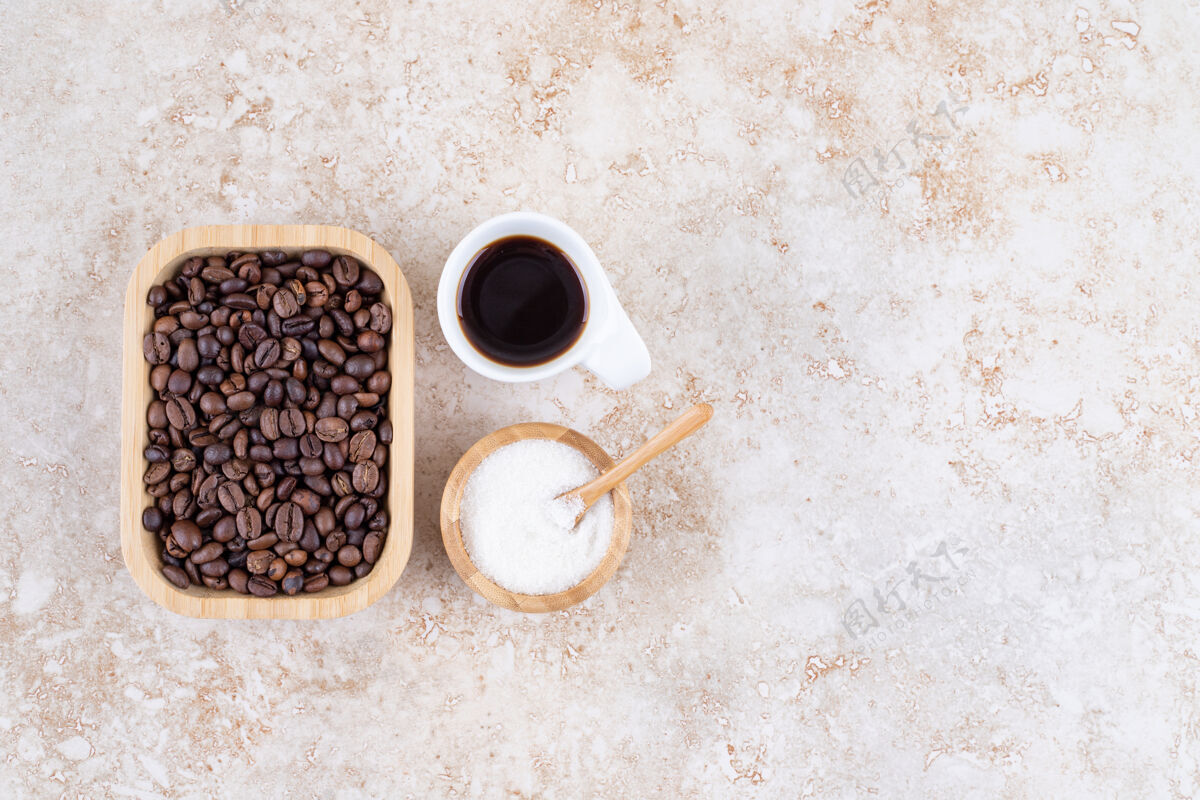 杯子一堆咖啡豆放在木盘里 旁边是一小碗糖和一杯咖啡芳香勺子咖啡