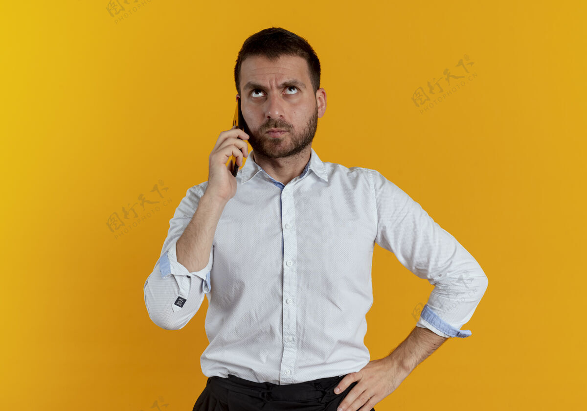优雅恼怒的帅哥在电话里说话 孤零零地看着橙色的墙上男士商务男士恼火