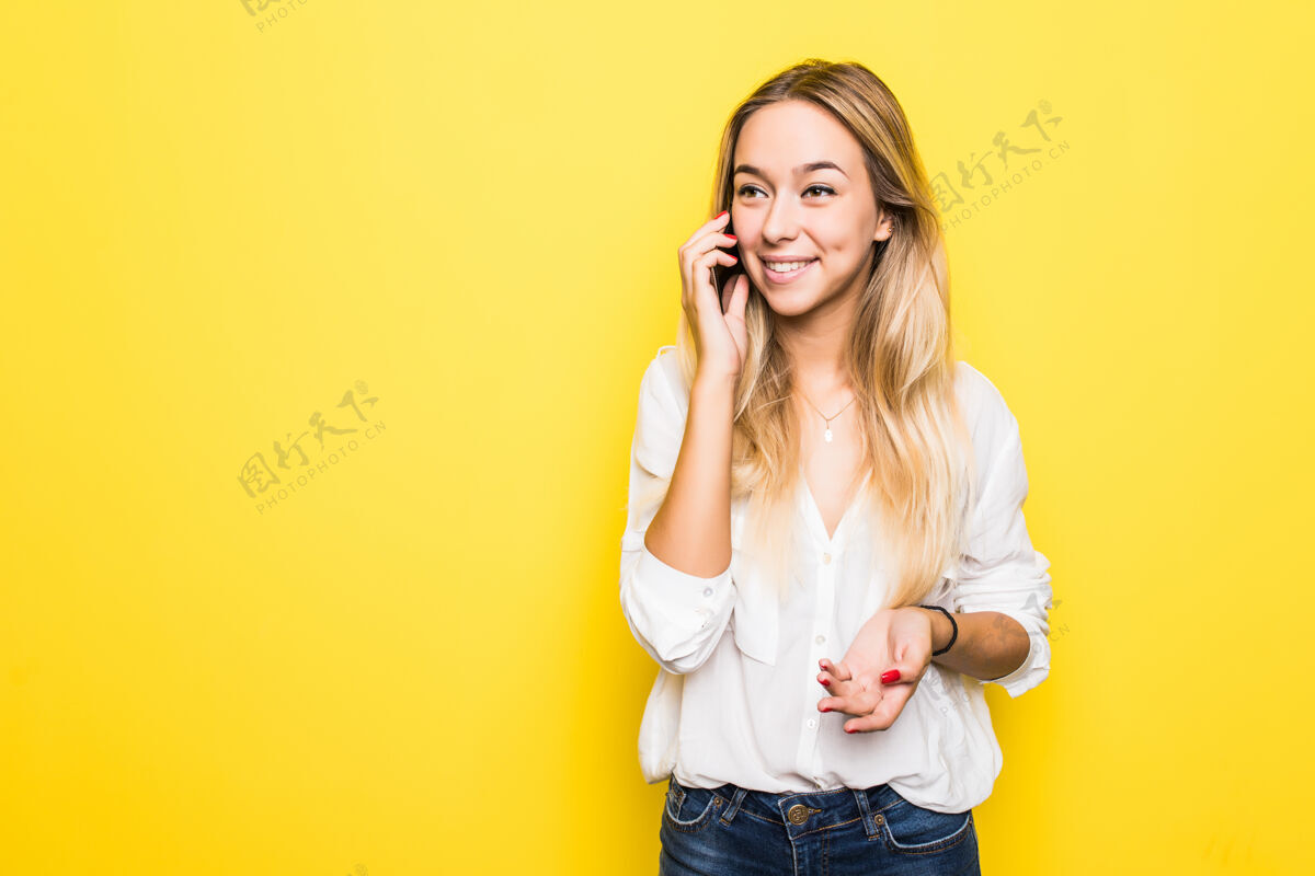 旁白快乐可爱的年轻女子用手机交谈的照片隔着黄色的墙欢呼手女士