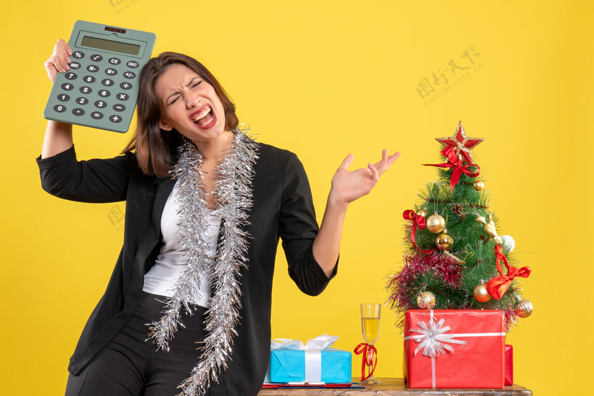 快乐圣诞气氛紧张美丽的女士站在办公室里拿着计算器在办公室里的黄色模特头发成人