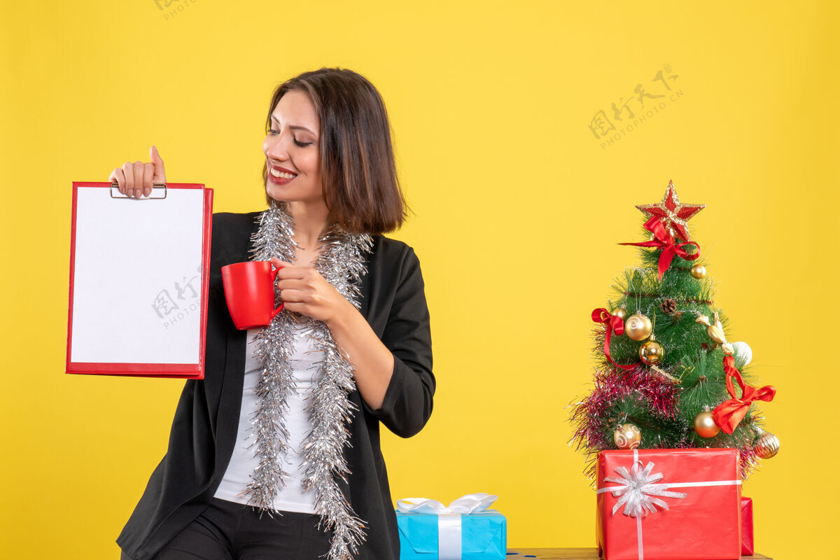 黄色圣诞气氛积极美丽的女士站在办公室里拿着文件杯在办公室里的黄色杯人心情