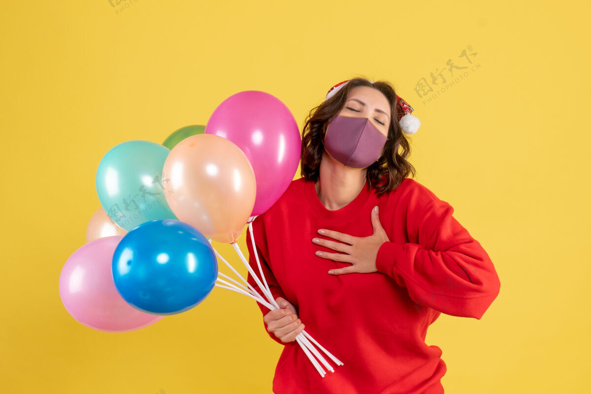 颜色正面图：戴着黄色面具手持气球的年轻女性面具生日磁盘骑师