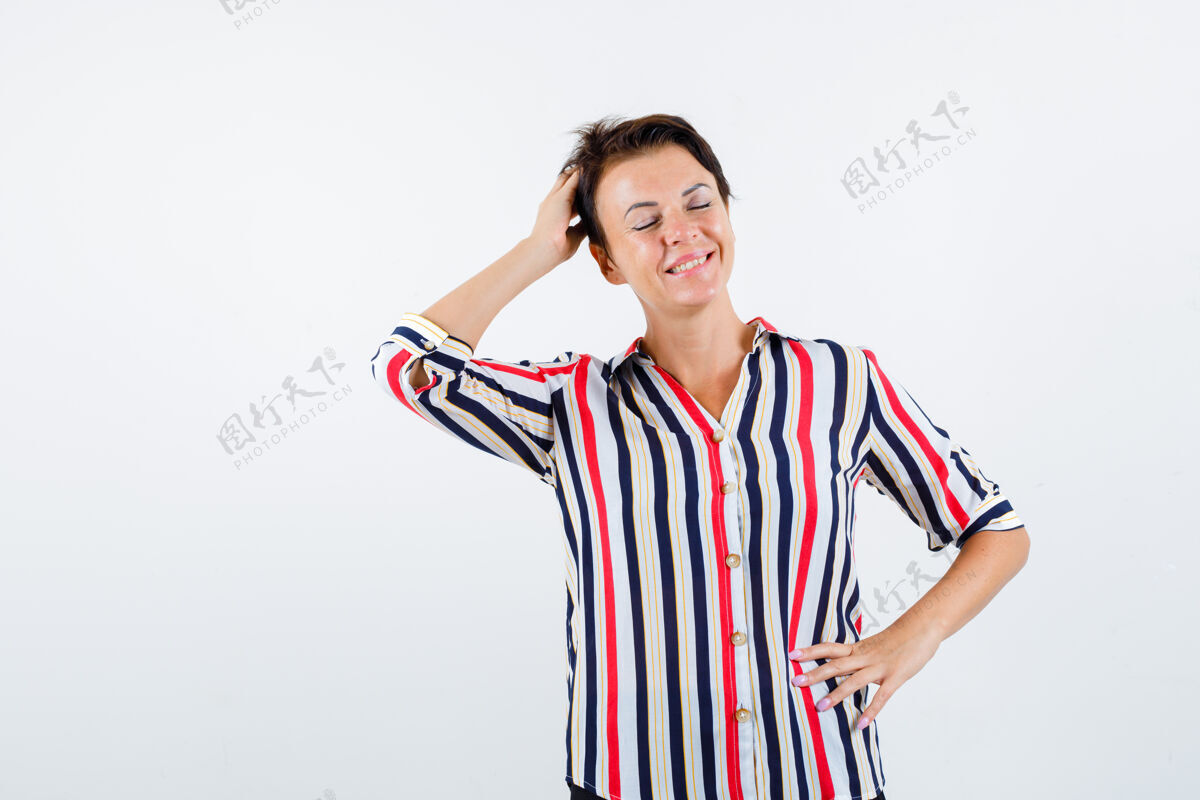 优雅成熟的女人一只手放在腰上 另一只手放在头上 闭上眼睛 穿着条纹衬衫 看起来很活泼正面图老年年龄前面