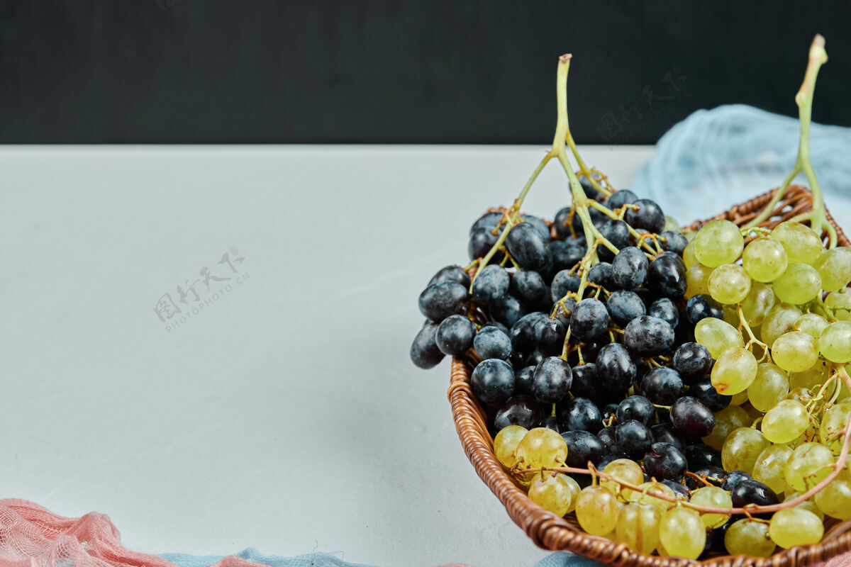 一串一簇混合的葡萄放在篮子里 蓝色和粉色的桌布高质量的照片美味正面视图优雅