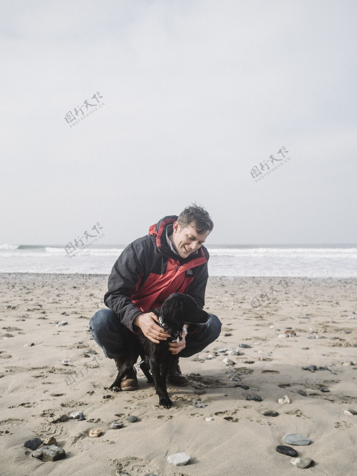 自然白天 雄性在沙滩上和一只可爱的黑色猎犬玩耍沙子狗海滩