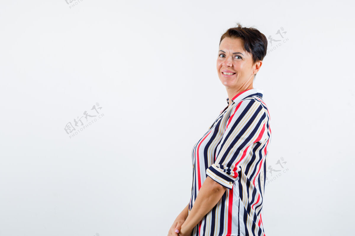 商务成熟的女人回头看 穿着条纹衬衫对着镜头摆姿势 看起来很有吸引力前视图年龄微笑条纹