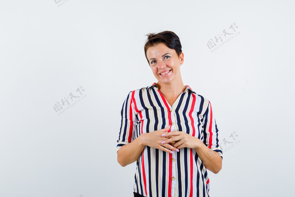 衬衫成熟的女人双手合十 穿着条纹衬衫微笑 看起来很乐观前视图扣人女人