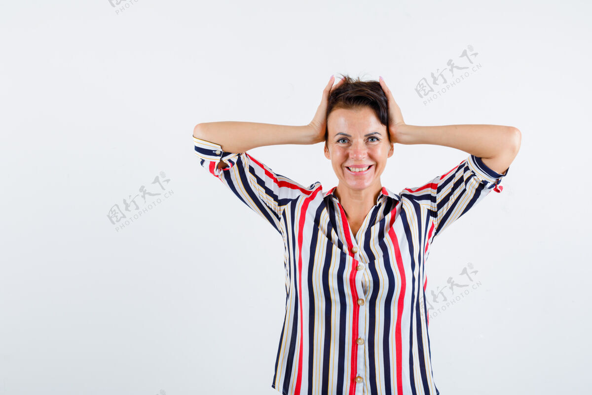 女人成熟的女人双手抱着头 穿着条纹衬衫 看起来很开心 正面照健康年龄成年人
