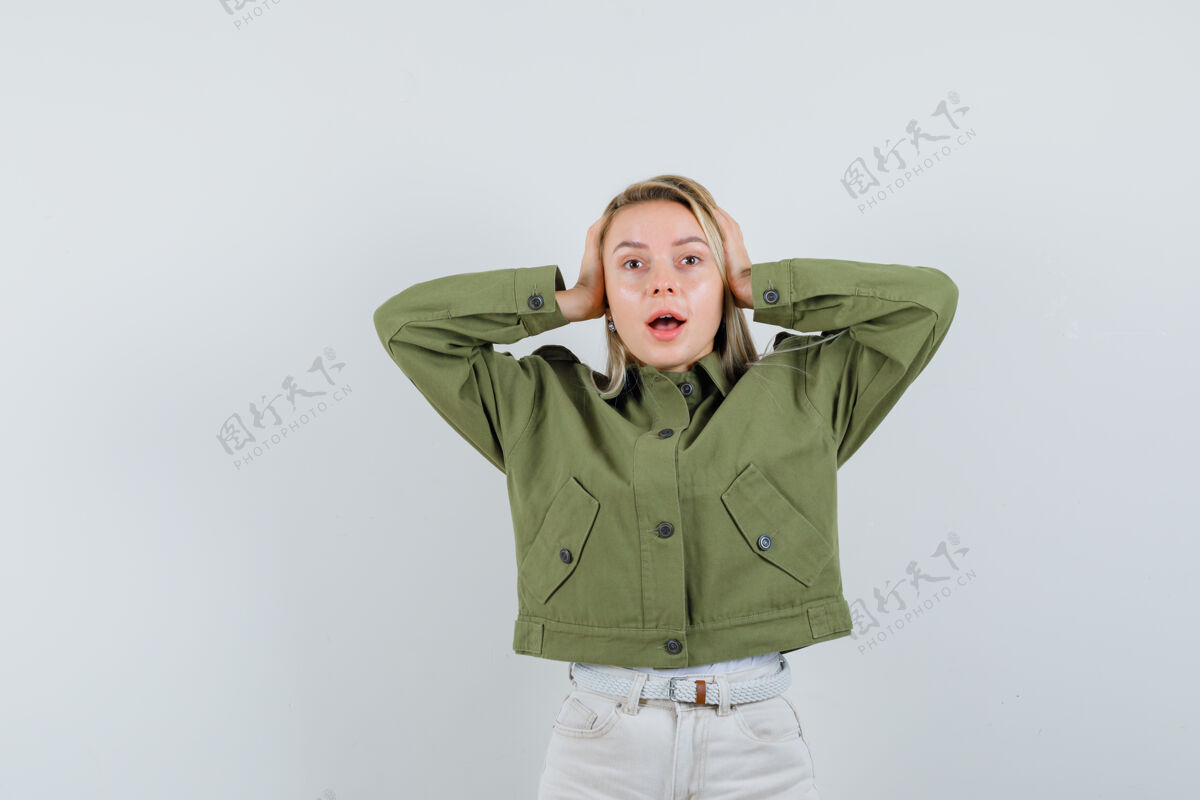 头发穿着绿色夹克的年轻女性 牛仔裤手放在耳朵上 看起来很有压力 前视图人夹克手