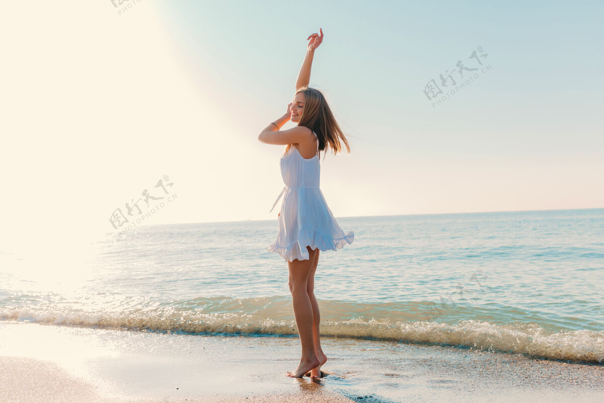 自然年轻迷人的快乐女子在海边跳舞转身阳光明媚的夏日时尚风格白色连衣裙活跃夜晚束腰外衣