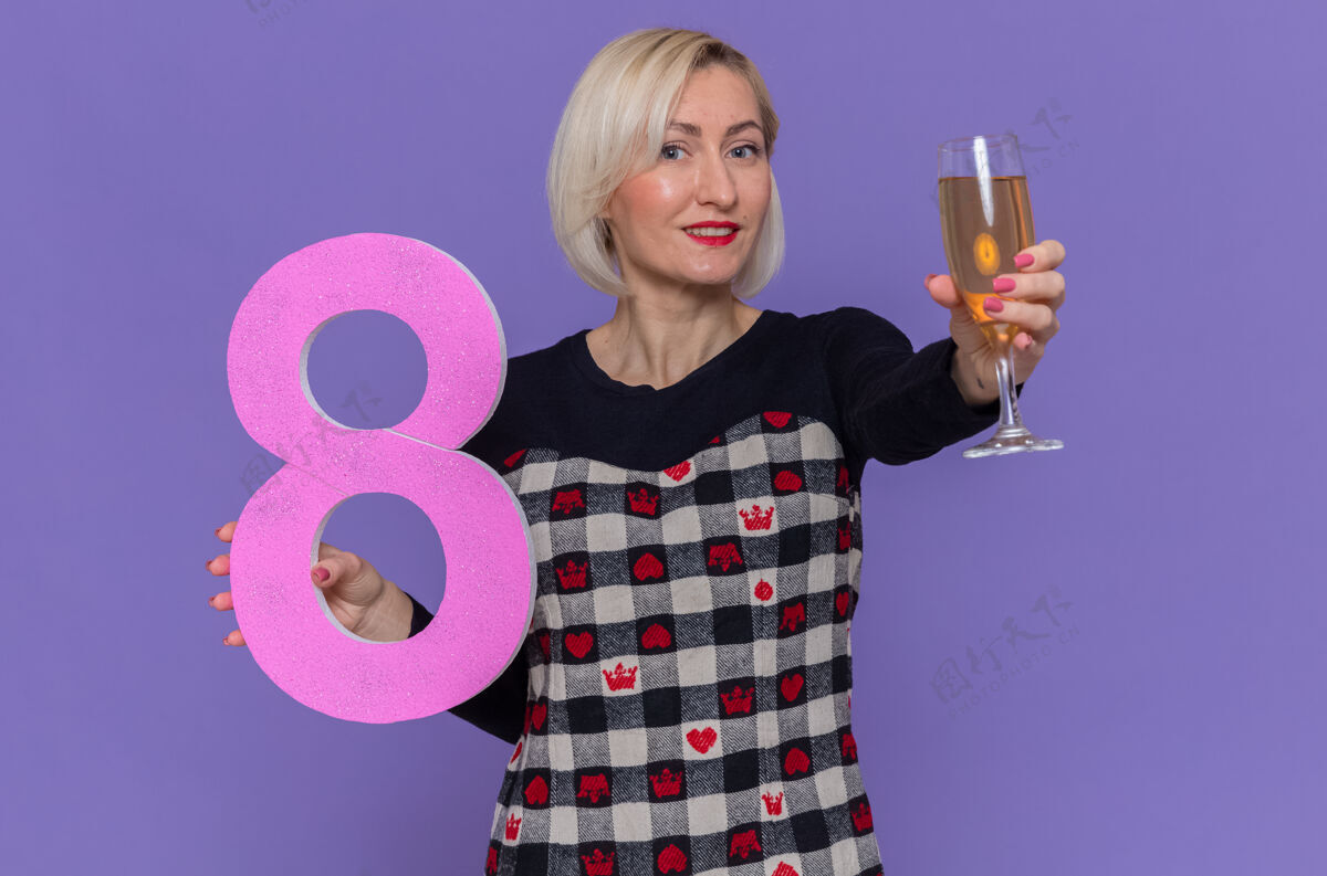 庆祝快乐的年轻女子拿着8号和一杯香槟微笑紫色三月
