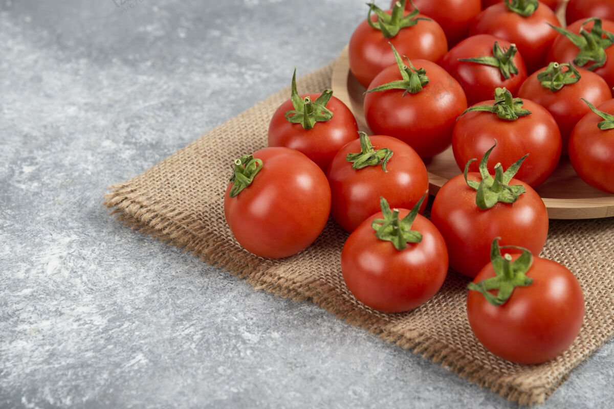 烹饪一堆红色的新鲜西红柿 用麻袋布铺在大理石表面多汁的天然红色