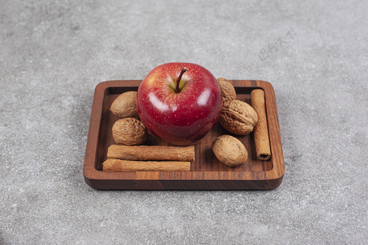 核桃红苹果 核桃和肉桂棒放在木盘上成熟的木材生的