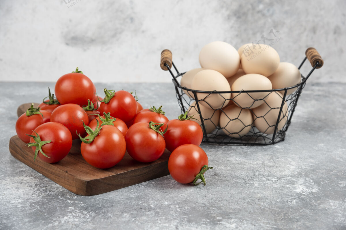 鸡蛋一篮子新鲜的生鸡蛋和成熟的西红柿放在大理石上鸡肉番茄烹饪