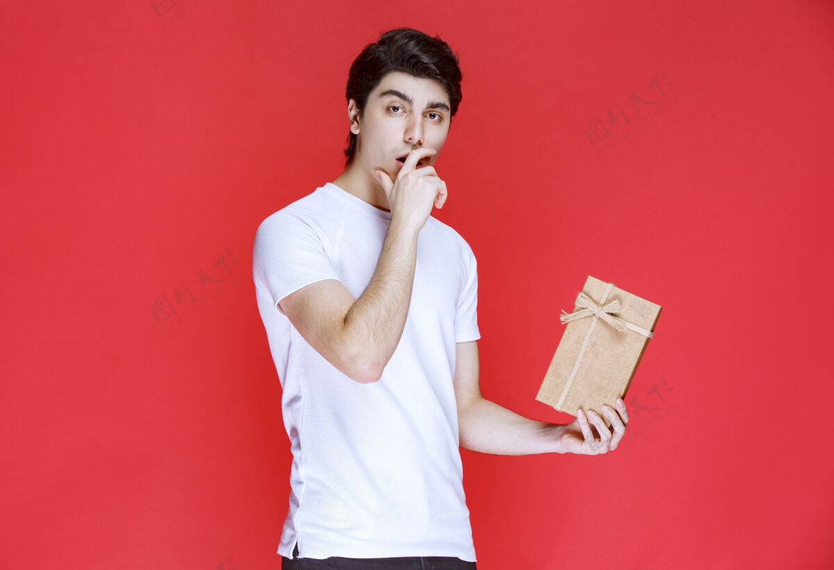 阳刚男人拿着一个纸板礼盒 看起来很困惑成人思考年轻