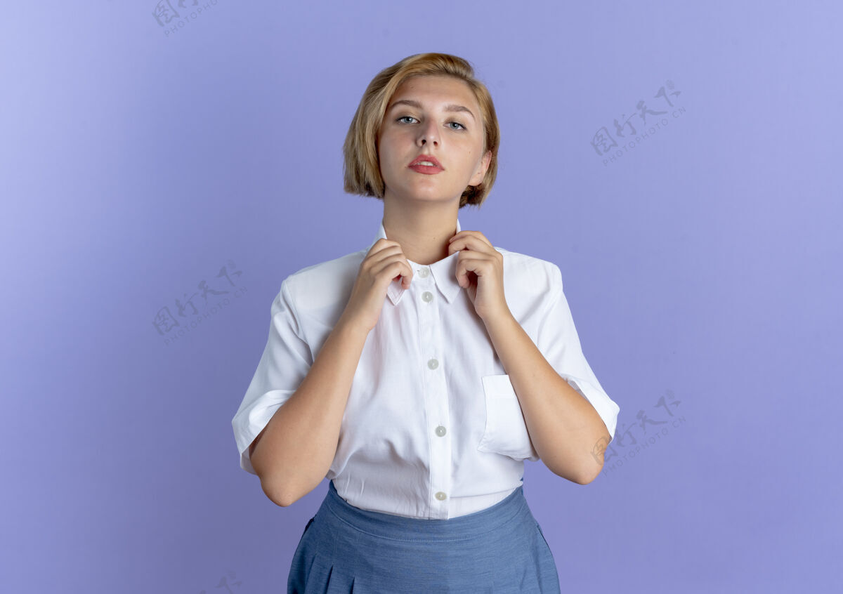 持之以恒年轻自信的俄罗斯金发女孩拿着衣领 看着隔离在紫色背景和复制空间的相机衣领年轻自信