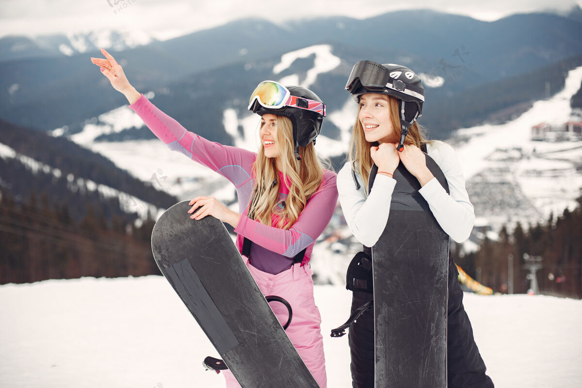 头盔穿着滑雪板套装的女人在山上的运动员手拿滑雪板在地平线上关于运动的概念人人金发