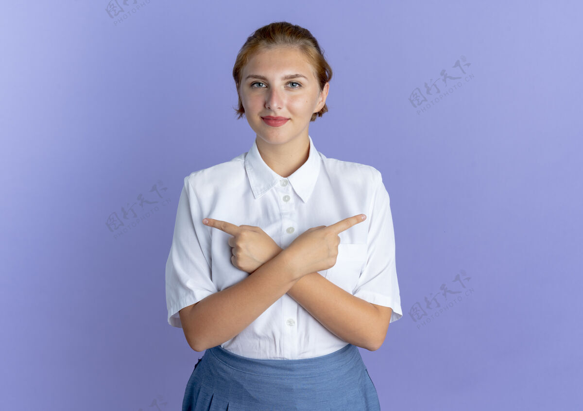 拜托年轻高兴的金发俄罗斯女孩点在双方孤立的紫色背景与复制空间尖侧翼年轻